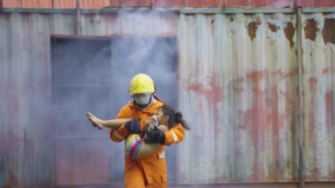 消防员携带并抱着亚洲小女孩，在里面发生火灾后，带着烟雾从房间的盖子里跑出来，把孩子带到安全的地方。