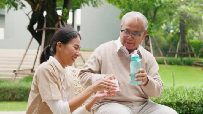年轻的亚洲女性照顾者，老人照顾者，老人在公园，服药后喝水，退休后治愈或治疗老年人的疾病，帮助支持。