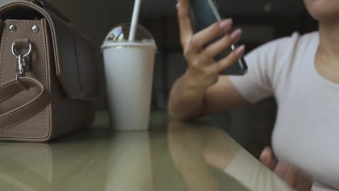 坐在咖啡店里的女人拿起她的智能手机开始说话。