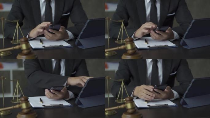 在线律师概念: 律师用平板电脑和旁边的金锤和秤来回应智能手机消息。