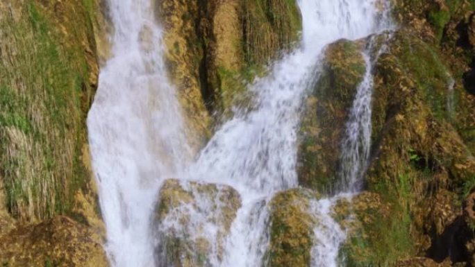 瀑布从石灰岩悬崖上流下的水的特写视图，带有棕色的铁沉淀物