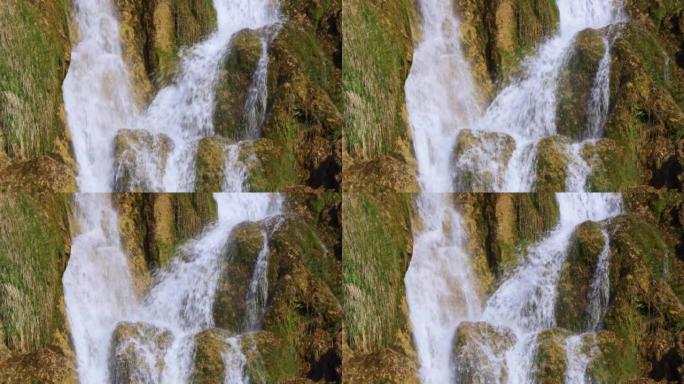 瀑布从石灰岩悬崖上流下的水的特写视图，带有棕色的铁沉淀物