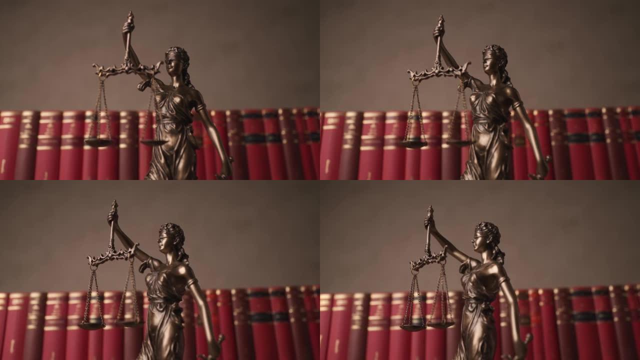 在以书籍为背景的大学教室里，蒙着眼睛的铜质法律女神手持象征公正和两大法律来源的天平和剑旋转着