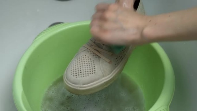 女人正在用手用海绵，特写手在盆子里洗运动鞋。