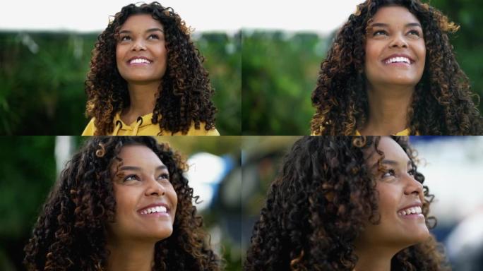 快乐的非洲裔美国女人特写脸仰望天空微笑。一个充满希望的20岁西班牙裔黑人成年女孩
