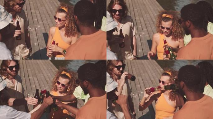 多样化的朋友在码头上碰碰啤酒瓶