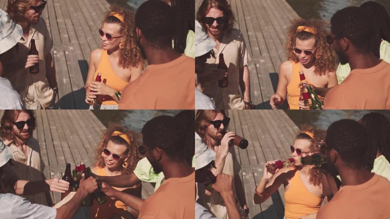 多样化的朋友在码头上碰碰啤酒瓶
