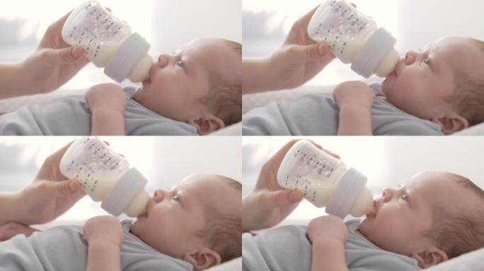 慈爱的母亲在家用奶瓶喂养小男孩，肖像婴儿婴儿吃饭，喝奶粉。