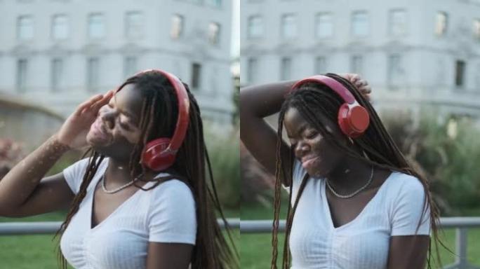 白癜风的非洲裔美国妇女在街上戴着耳机听音乐时微笑着跳舞。
