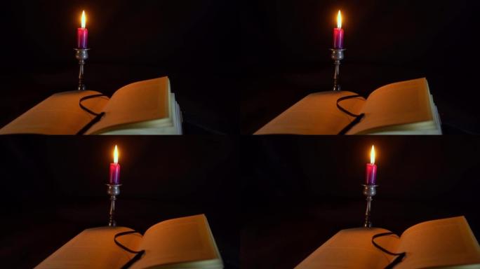 平底锅在一本打开的书，其中后面是一个燃烧的短勃艮第蜡烛在一个锡烛台，黑暗的气氛