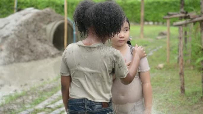 孩子们在社区田野里玩泥巴滑梯后洗泥。父母从远处看着