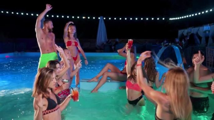 朋友在私人别墅游泳池举行夜间泳池派对。穿着泳装的开朗年轻人在豪华度假胜地泼水，跳舞和聚会。快乐的男人
