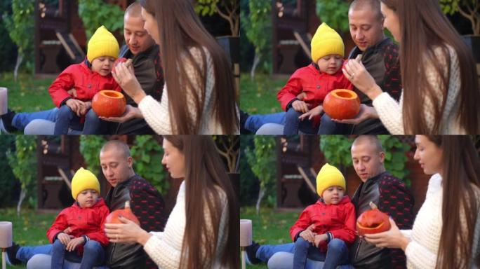 微笑的父亲和好奇的儿子看着万圣节南瓜，母亲的妻子以慢动作打开蔬菜。快乐的男人和男孩喜欢和女人在户外后