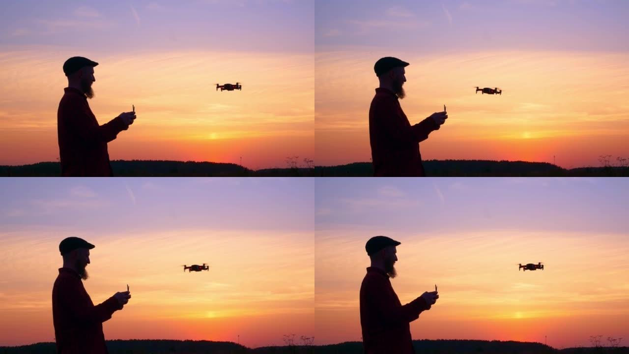 一个控制无人机飞行进行侦察的人的剪影。无人机在明亮的日落天空中左右移动。使用新技术的概念。