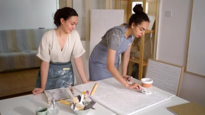 高加索姐妹，在他们的艺术工作室用画布上的丙烯酸腻子制作艺术作品