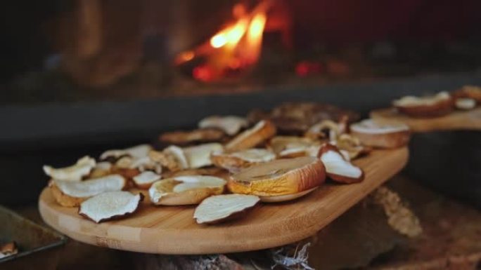 用燃烧的木头在温暖的壁炉在木板上干燥的蘑菇切片