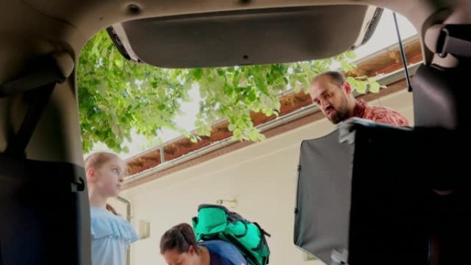 父母和女儿用手推车和行李装载汽车后备箱