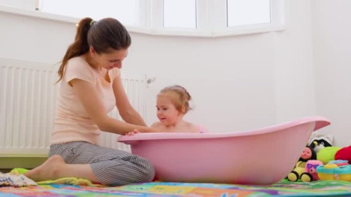 妈妈洗澡小女儿洗她的背宝宝玩水把她的杯子变成面对妈妈。