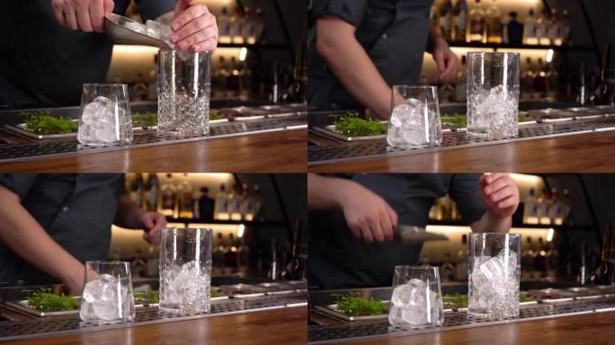 酒保在带有冰勺的玻璃杯中添加冰块，用于制作酒精鸡尾酒。