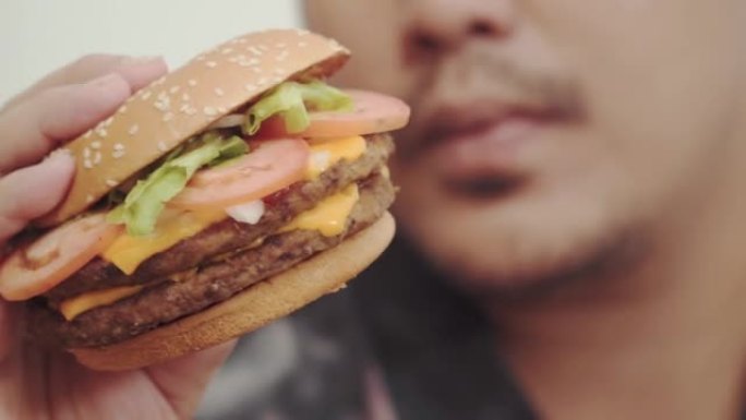 特写镜头喜欢吃汉堡的年轻人。享受不健康的饮食