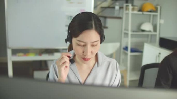 可爱的女性呼叫中心代理在她的工作站上与客户交谈