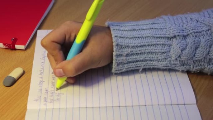 学生用英语写的笔记本上的手的特写。