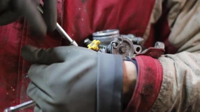 男子诊断和修理燃油系统摩托车化油器。化油器和节气门服务。