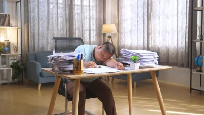 肥胖的亚洲男子因在办公室努力工作而睡觉