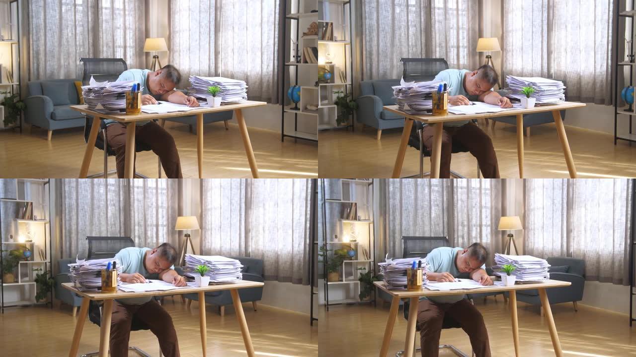肥胖的亚洲男子因在办公室努力工作而睡觉