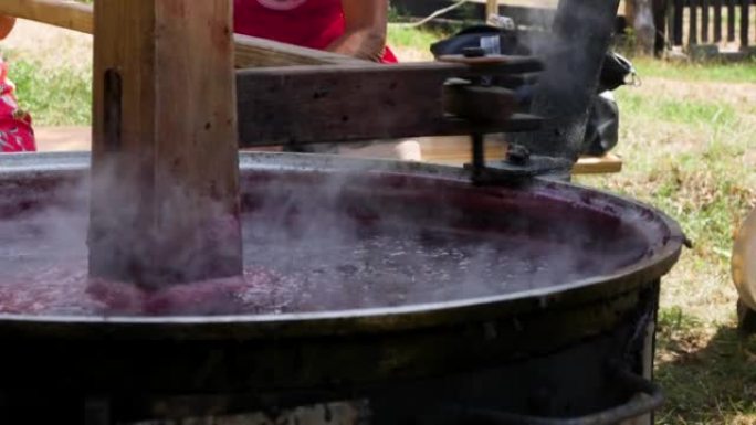 用传统的大锅煮李子果酱。用 “帆” 混合器在传统大锅中果酱。户外制作梅花果酱的正宗工艺
