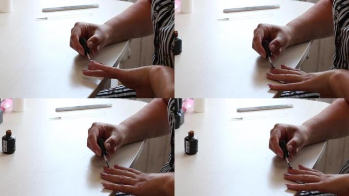 女人涂指甲油。修指甲。桌子旁边是一罐清漆。在窗户的背光中拍摄