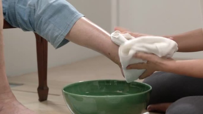 女性护理员用生理盐水按摩和清洁老年妇女的脚。