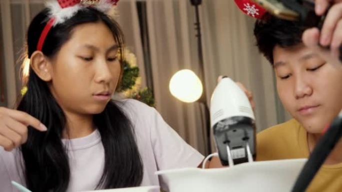 亚洲儿童在圣诞节期间在家拍摄烹饪饼干视频，以获取病毒视频或在家里一起拍摄YouTube，这是新一代概