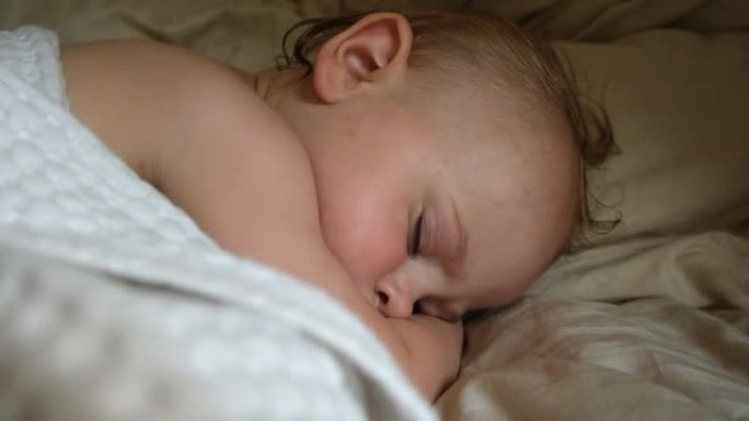 和平可爱的婴儿睡在家里的床上。睡眠新生儿概念。一岁的女婴在家庭室内背景下安静地睡觉。宁静的梦。脸特写