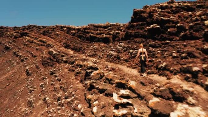 女人旅行者走过卡尔德隆·洪多火山的熔岩场火山口。西班牙加那利岛富埃特文图拉。去任何地方。另一个星球的