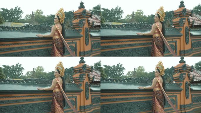 美丽的巴厘岛妇女站在橙色的墙壁上，穿着传统的巴厘岛服装和金色的皇冠