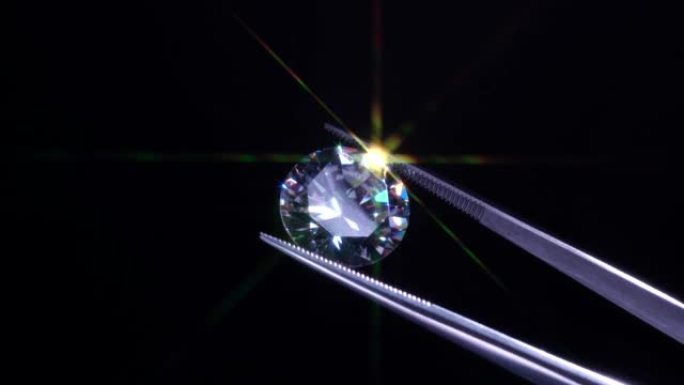 钻石选择性聚焦在金属珠宝商镊子中，明亮的石头切割有星形光射线爆发，星爆或阳光。波兰质量和污染检查。碳