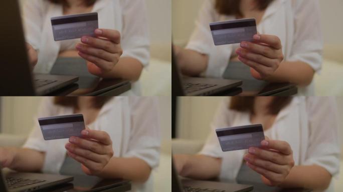 特写怀孕的亚洲妇女在家里用笔记本电脑用信用卡付款。