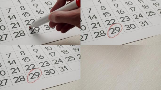 人的手用红笔在纸质日历上写下第29天。