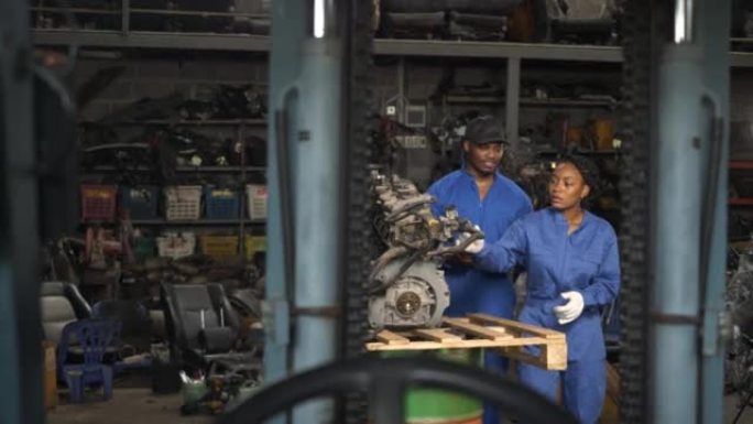 非裔美国男女合伙人拥有汽车修理厂。背部男女修理工检查汽车维修。两个机械师在检查汽车发动机。 一男一女