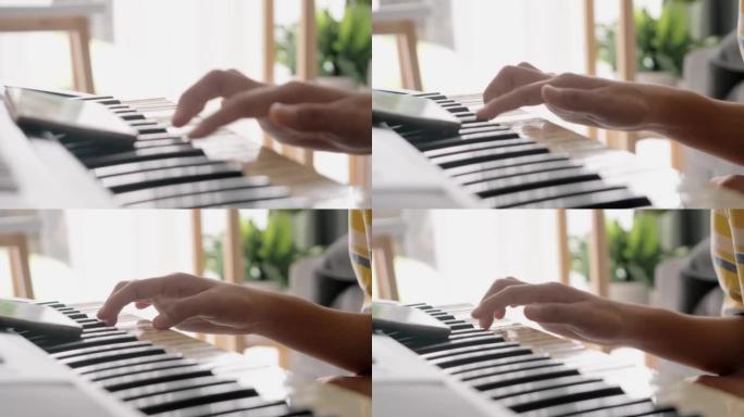 女孩在家靠窗的沙发上通过移动应用学习弹奏键盘乐器，生活方式概念。身体部位。