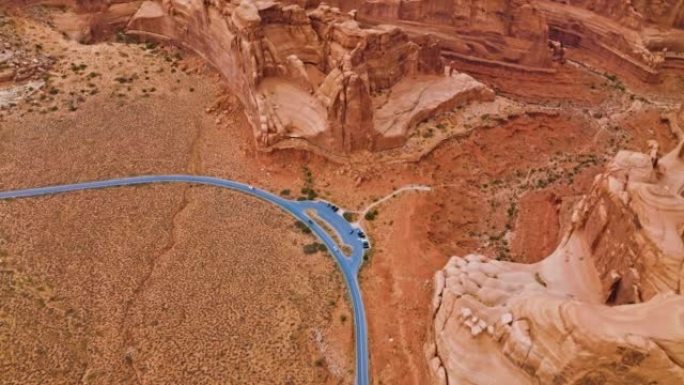穿越红色干燥沙漠的公路灰色线。美国犹他州峡谷上空的无人机镜头。