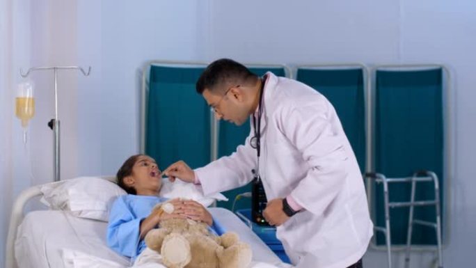 一名印度男性医生用压舌板检查小女孩的喉咙是否有感染-医学检查，儿科医生