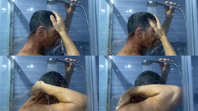 一个男人在浴室里用泡沫洗发露冲洗头发。一名年轻男子在淋浴时用慢动作去除头发上的肥皂的视频。