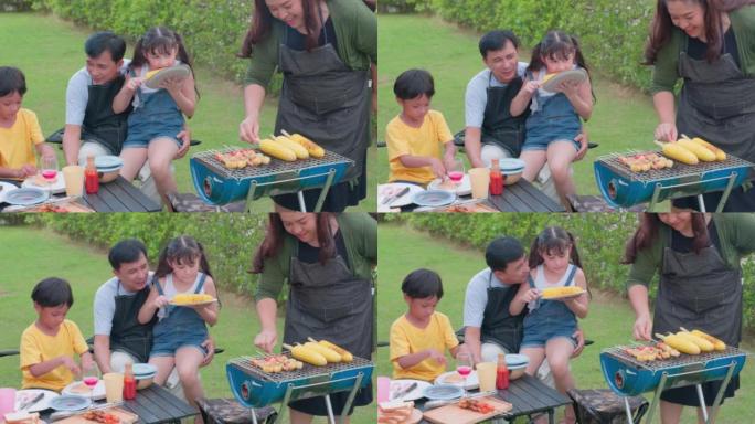妈妈在夏季聚会上在甜玉米烤架上烤肉，快乐的亚洲家庭在他们的后院举行烧烤派对。