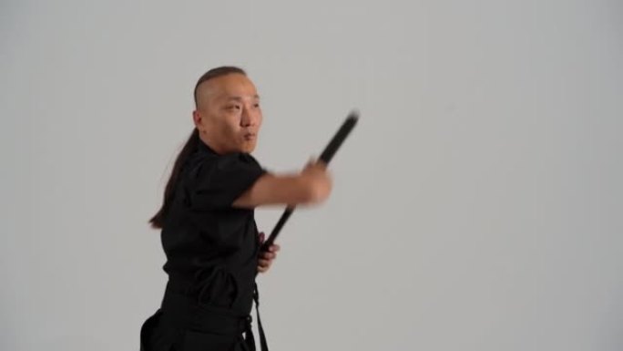 日本武士穿着黑色和服，手里拿着武士刀，在白色的画室里