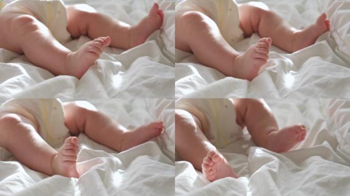 婴儿腿紧贴在白色毯子上。健康的新生脚。温暖的阳光。婴儿小脚在浅色背景上的美丽照片。幼儿发育。真实的坦