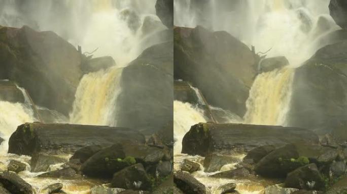 单宁水的框架填充镜头落在长岩石上，并在白水瀑布底部的巨石之间流动