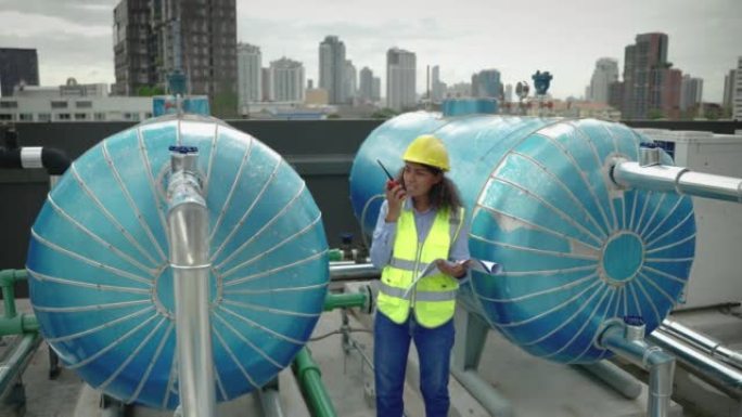 工程师在摩天大楼的屋顶上检查冷却系统的管道。按行业标准检验的概念，工程、施工。