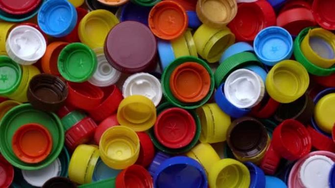 顶视图塑料盖的废物堆。旋转背景的垃圾塑料多色盖子。不同颜色的盖子用于塑料回收。